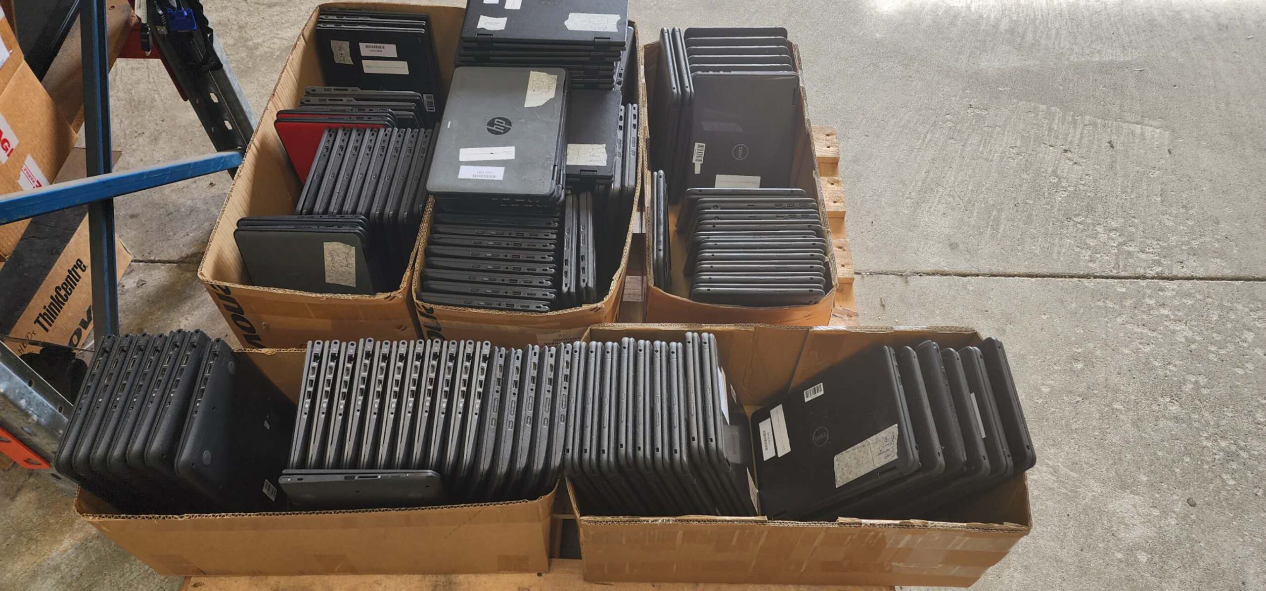 Boxes of retired HP, Dell and Lenovo laptops on a warehouse pallet