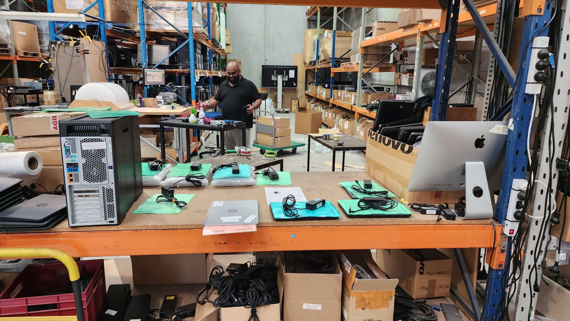 A team member working behind a warehouse bench with laptops and chargers